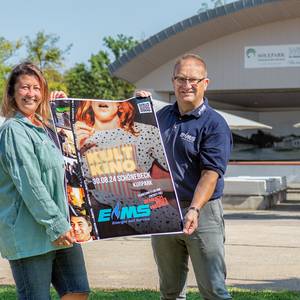 Jessika Rogat vom SOLEPARK und EMS-Pressesprecher Frank Sieweck präsentieren vor der Kurparkbühne das aktuelle Plakat zum diesjährigen Kult-Kino. Gezeigt wird am 30. August „Ziemlich beste Freunde“. Der Eintritt ist frei! © Solepark Kult-Kino