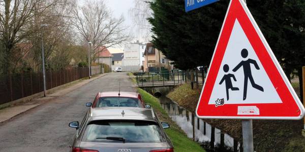 Am kommenden Montag erfolgt der Baustart in der Straße "Am Gänsewinkel". © Stadt Schönebeck (Elbe) Zwei Autos stehen auf einer Schotterstraße neben einem Wassergraben.