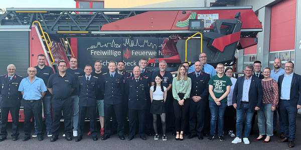 Feuerwehrmänner und -frauen stehen vor einem Feuerwehrauto.