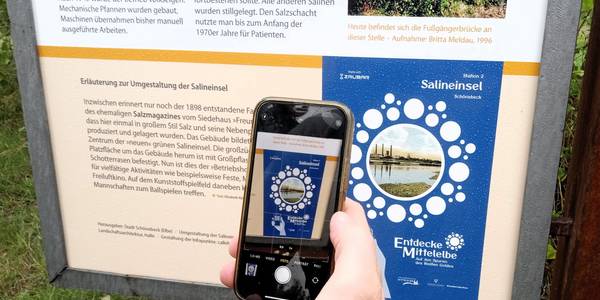 QR-Code scannen, AR bestätigen und eintauchen in die Geschichte mithilfe der AR-Technologie. © Stadt Schönebeck (Elbe) Ein Handy scannt einen Code für AR ein.