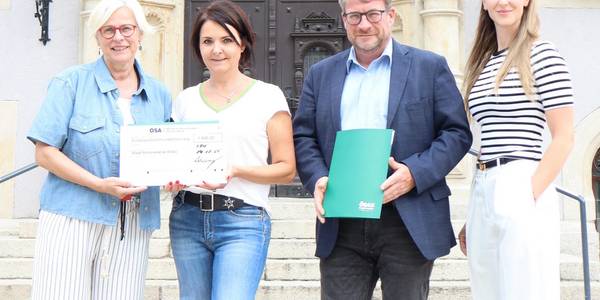 Eim Mann und drei Frauen stehen vor dem Schönebecker Rathaus und halten einen symbolischen Spendenscheck.