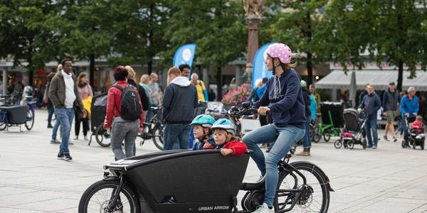 Ein Mann transportiert zwei Kinder mit einem Lastenrad.