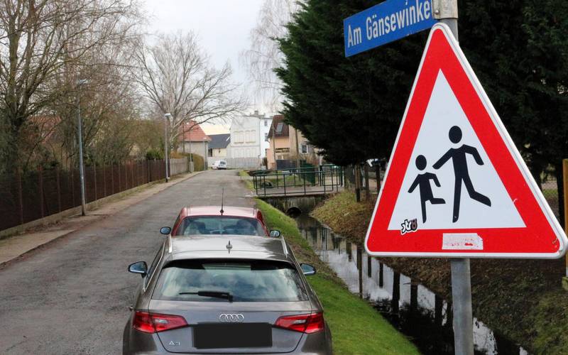 Zwei Autos stehen auf einer Schotterstraße neben einem Wassergraben.