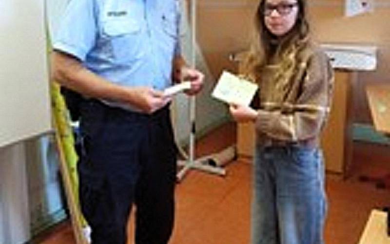 Ein Polizist und eine Schülerin der 4. Klasse mit einem Fahrradführerschein.