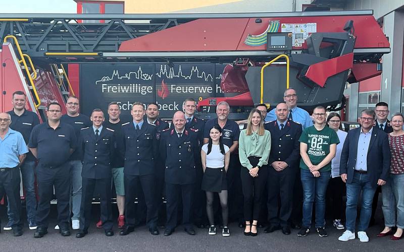Feuerwehrmänner und -frauen stehen vor einem Feuerwehrauto.