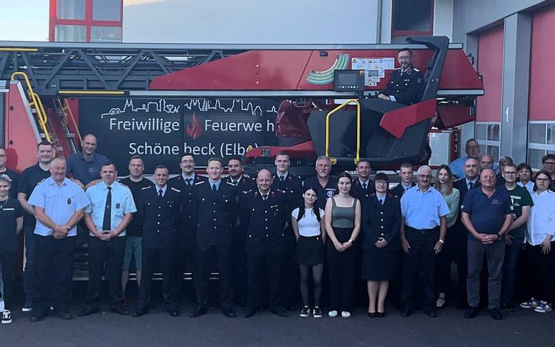 Feuerwehrmänner und -frauen stehen vor einem Feuerwehrauto.